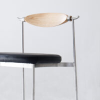 A modern chair with a black cushioned seat, slim metal frame, and a curved wooden backrest, set against a plain light background.