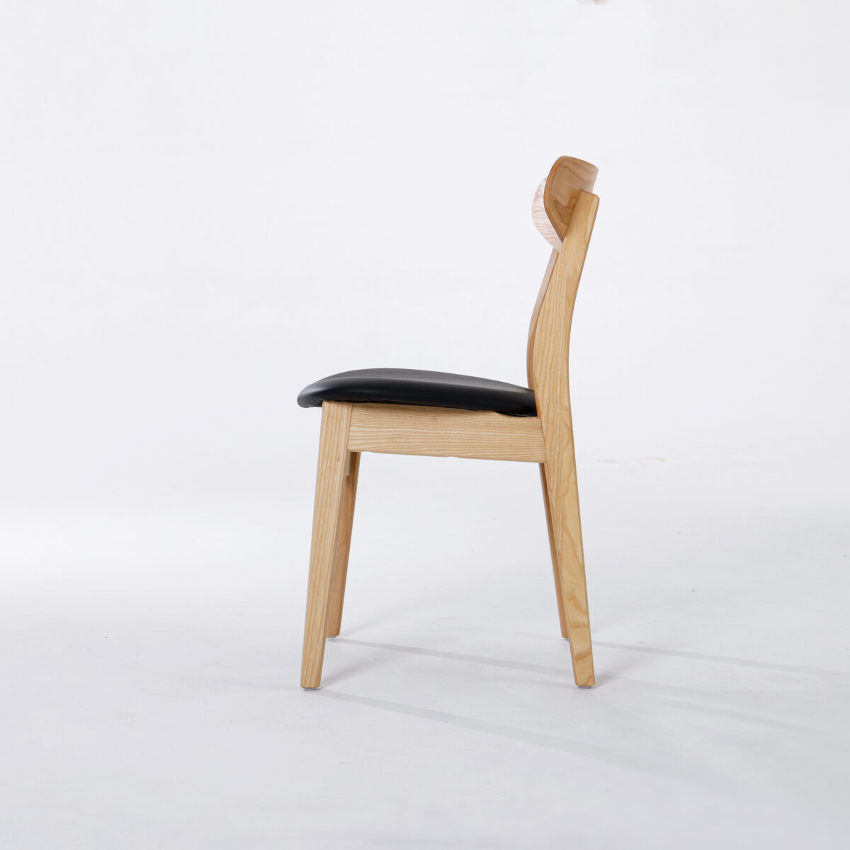 CH30P Chair_B20 A wooden chair with a light-coloured frame, a slightly curved backrest, and a black cushioned seat, shown in profile against a plain white background.