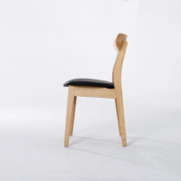 A wooden chair with a light-coloured frame, a slightly curved backrest, and a black cushioned seat, shown in profile against a plain white background.