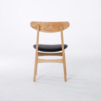 A wooden chair with a curved backrest and a black cushioned seat, shown from the back on a plain white background.