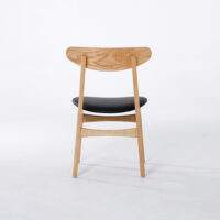 A wooden chair with a curved backrest and a black cushioned seat, shown from the back on a plain white background.