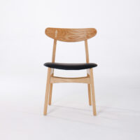 A wooden chair with a curved backrest and light wood finish, featuring a black upholstered seat, set against a plain white background.