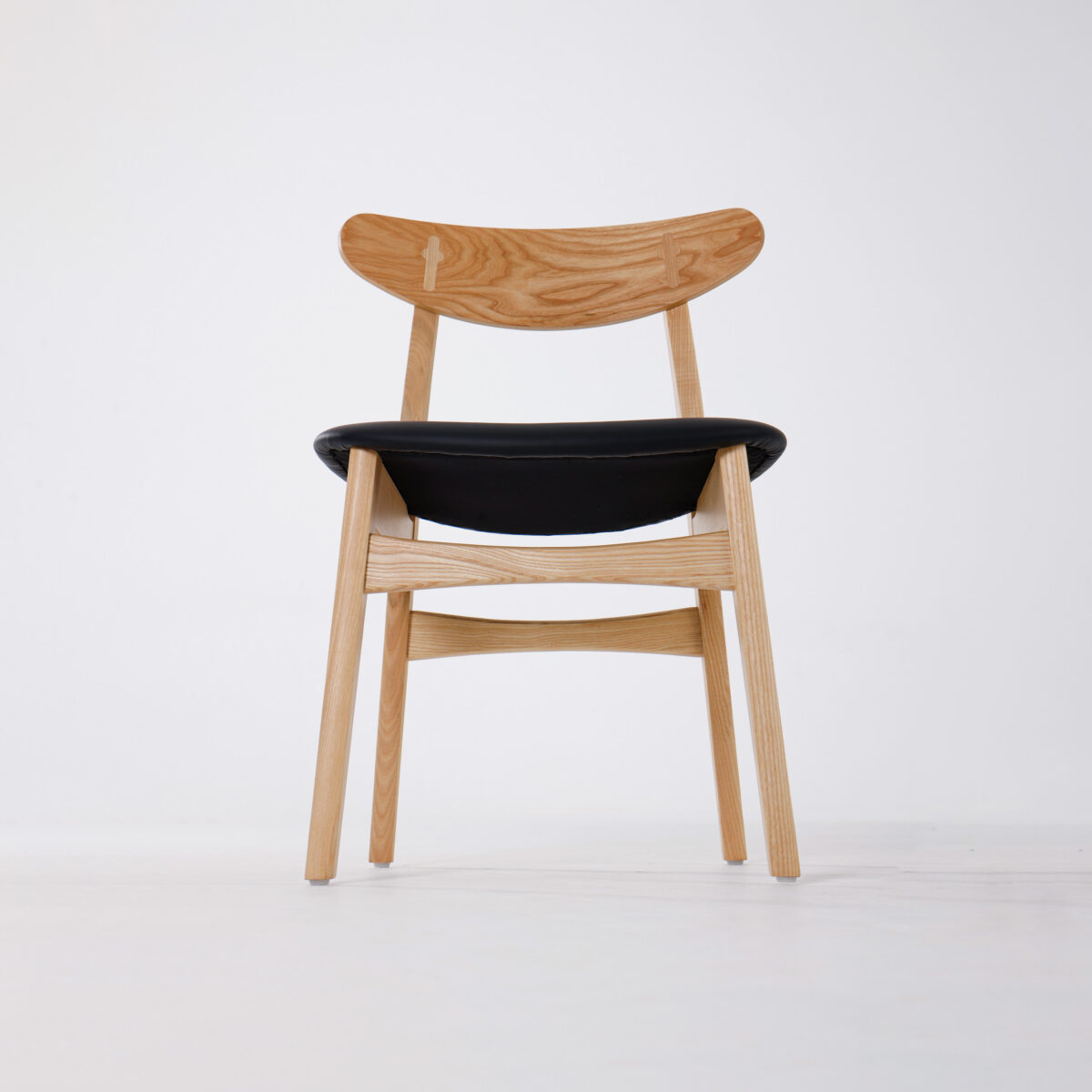 CH30P Chair_B6 A modern wooden chair with a curved backrest and a black upholstered seat, photographed against a plain white background.