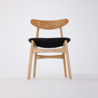A modern wooden chair with a curved backrest and a black upholstered seat, photographed against a plain white background.