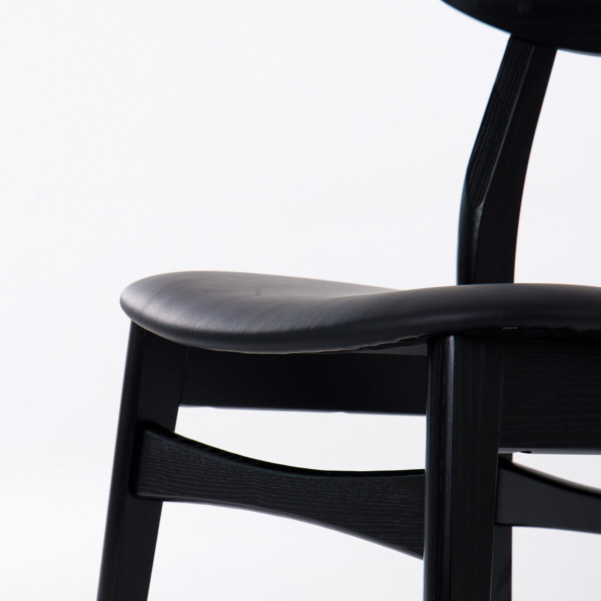 CH30P Chair_Black_B9 Close-up of a modern black wooden chair with a curved seat and backrest, photographed against a plain white background.