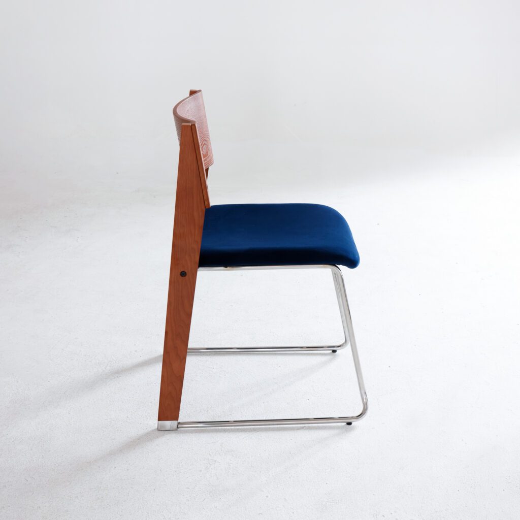 A modern chair with a wooden backrest, blue cushioned seat, and metal legs is shown from the side against a plain white background.