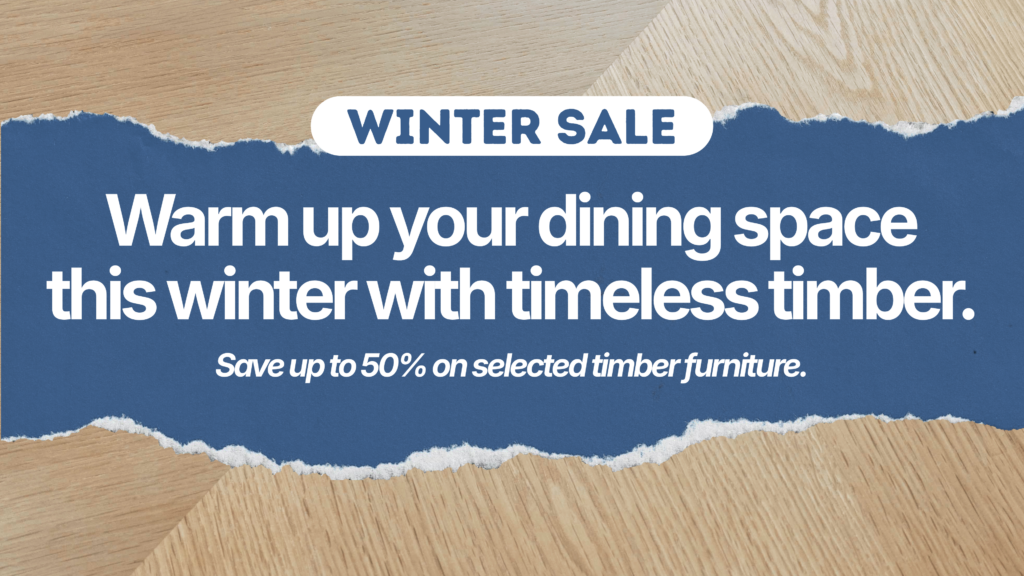 A winter sale advert on timber furniture, offering up to 50% off. Text reads: Warm up your dining space this winter with timeless timber. The background shows torn paper effects over wooden textures.